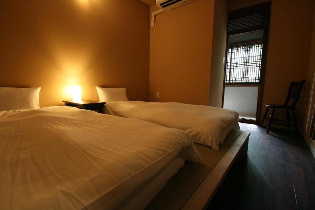 a bedroom with two beds and a chair and a window at HARUYA Naramachi in Nara
