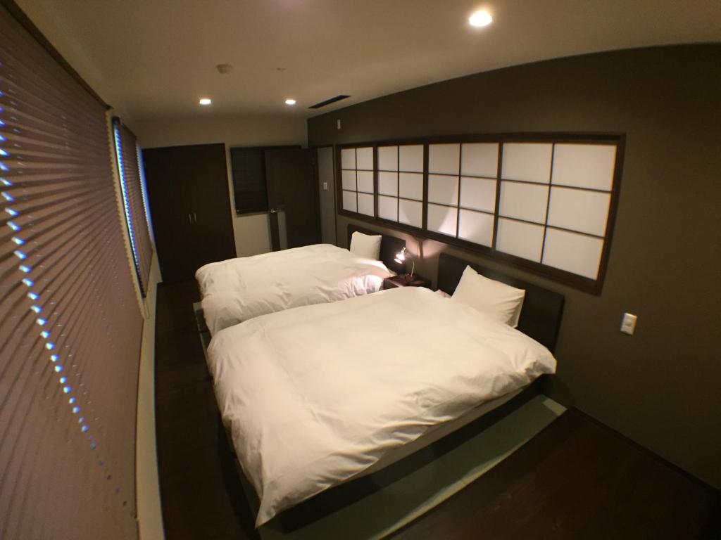 two beds in a small room with a window at Hokuriku Yamashiro Onsen Hotel Kikyou in Yamashiro