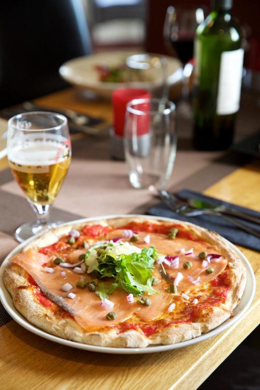 a pizza on a plate on a table with a glass of wine at LOCH TAY HIGHLAND LODGES and GLAMPING PARK in Morenish