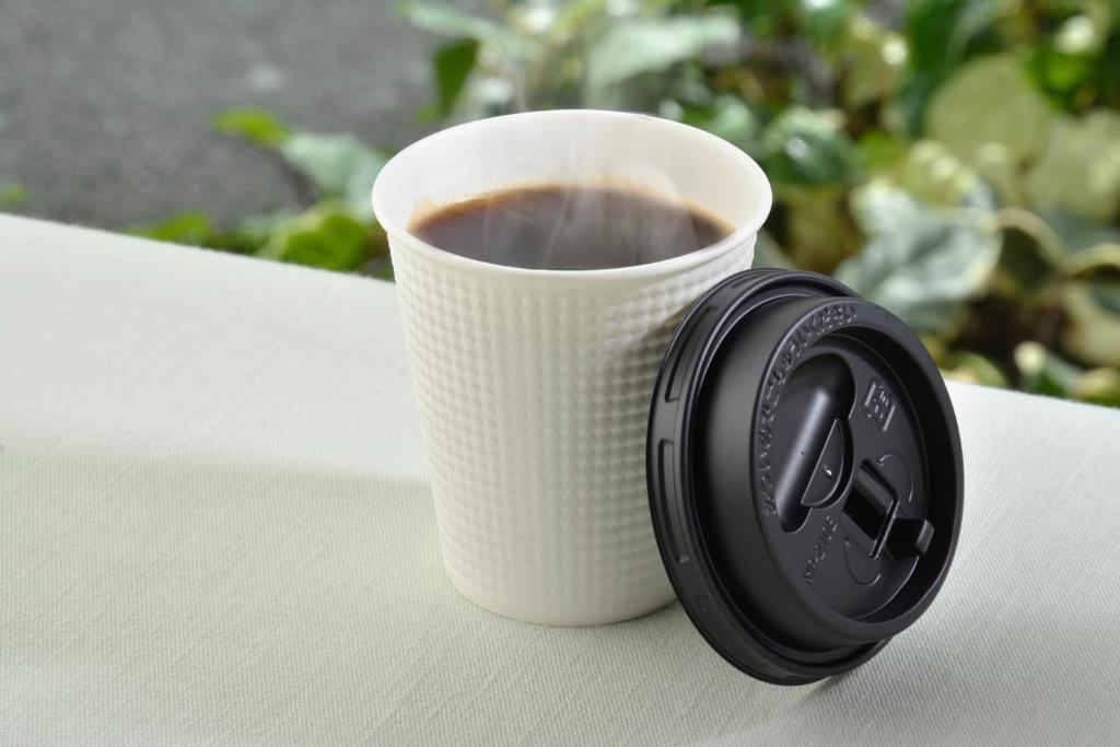 a cup of coffee sitting on a table next to a headphone at Premier Hotel Cabin Shinjuku in Tokyo