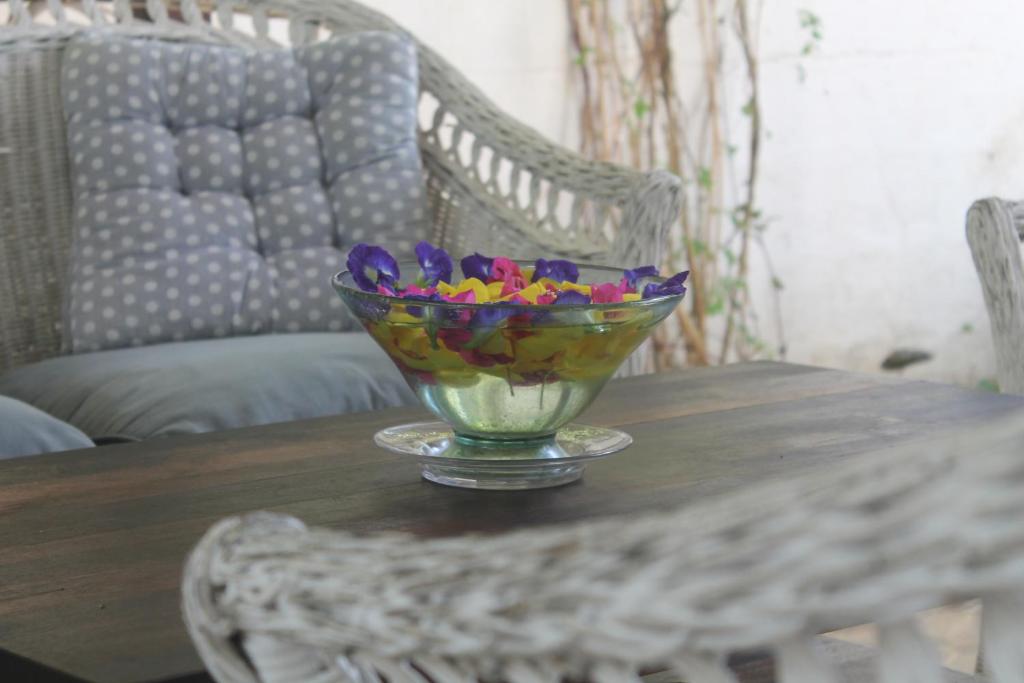 a glass bowl of flowers on a wooden table at Auberge Miko in Grand Baie