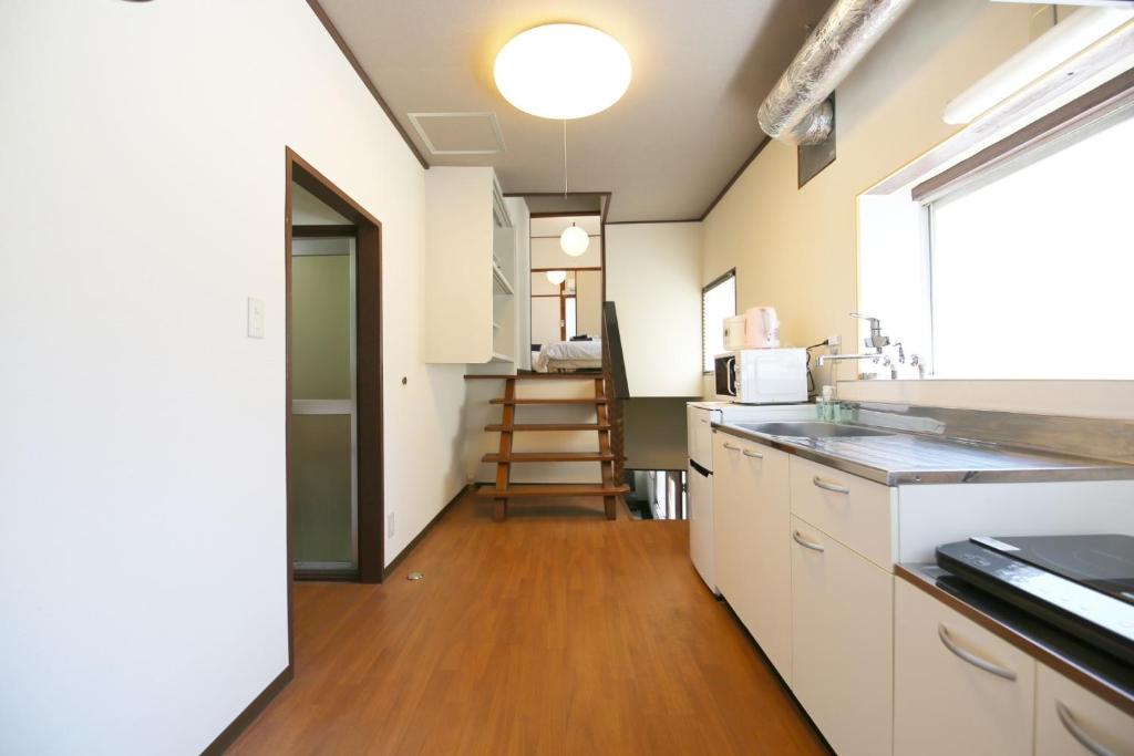a kitchen with white cabinets and a wooden floor at Hakone No Yado in Hakone