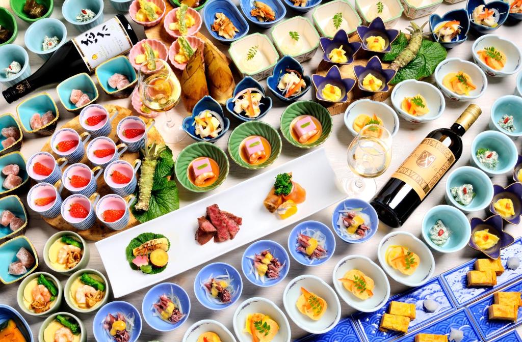 a table filled with dishes of food and a bottle of wine at Hotel Laforet Shuzenji in Izu