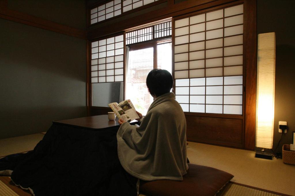 a woman in a robe looking out of a window at HARUYA Naramachi in Nara