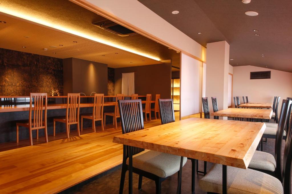 a restaurant with a wooden table and chairs at Hokuriku Yamashiro Onsen Hotel Kikyou in Yamashiro