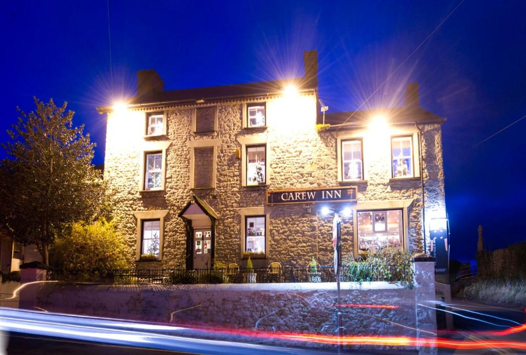 a large stone building with lights on it at night at Carew Inn in Tenby