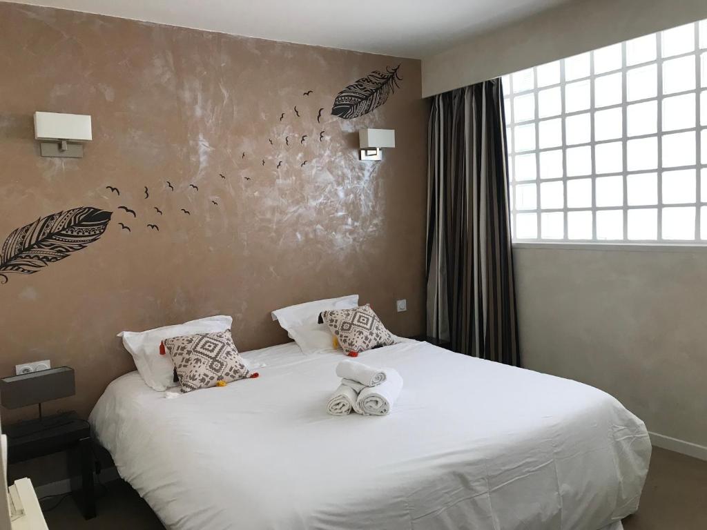 a bedroom with a bed with white sheets and butterflies on the wall at ALBI HOME - Vigan in Albi