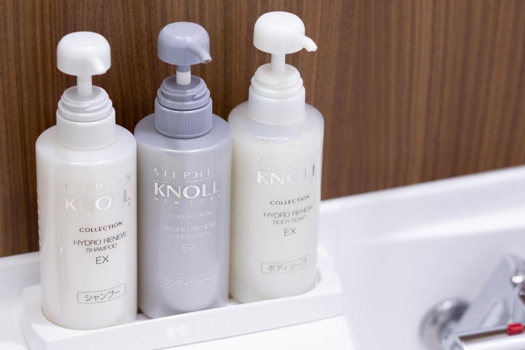 three white bottles sitting on a shelf in a bathroom at Shibuya Tokyu REI Hotel in Tokyo
