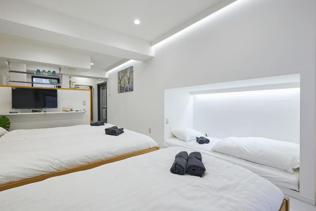 two beds in a room with two pairs of shoes on them at STAY ARI Kabukicho in Tokyo