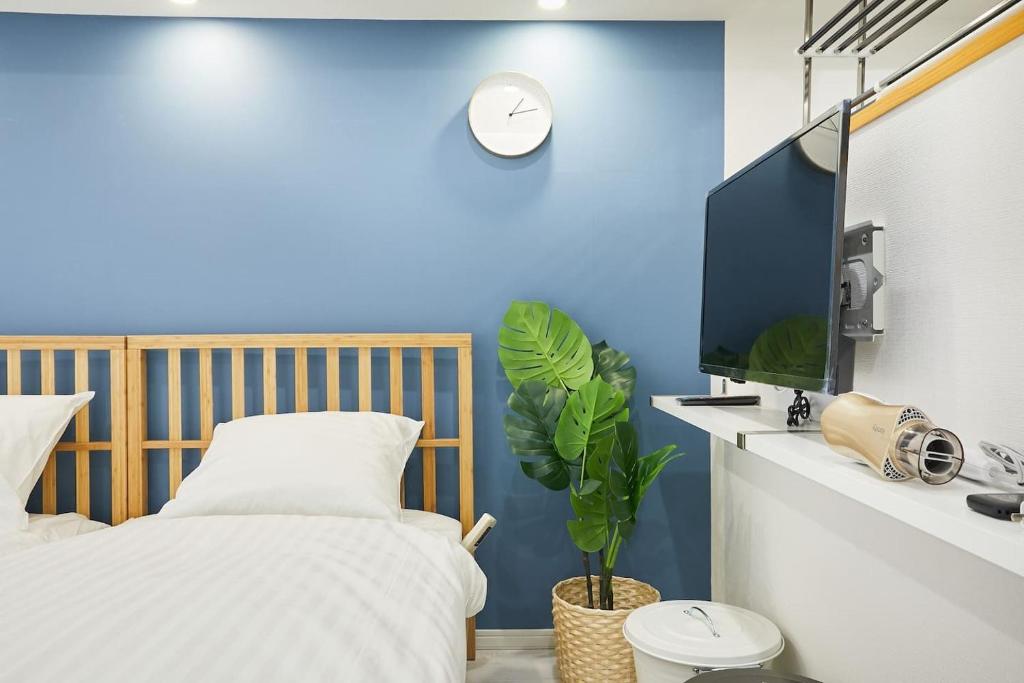 a bedroom with a blue wall and a bed and a tv at STAY ARI Kabukicho in Tokyo