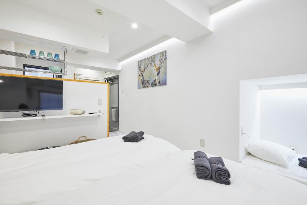two white beds in a room with a flat screen tv at STAY ARI Kabukicho in Tokyo