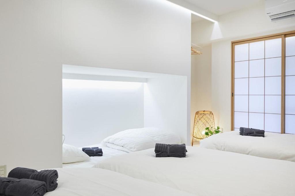 two beds in a white room with a window at STAY ARI Kabukicho in Tokyo