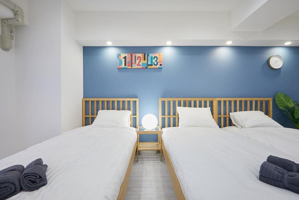 two beds in a room with a blue wall at STAY ARI Kabukicho in Tokyo