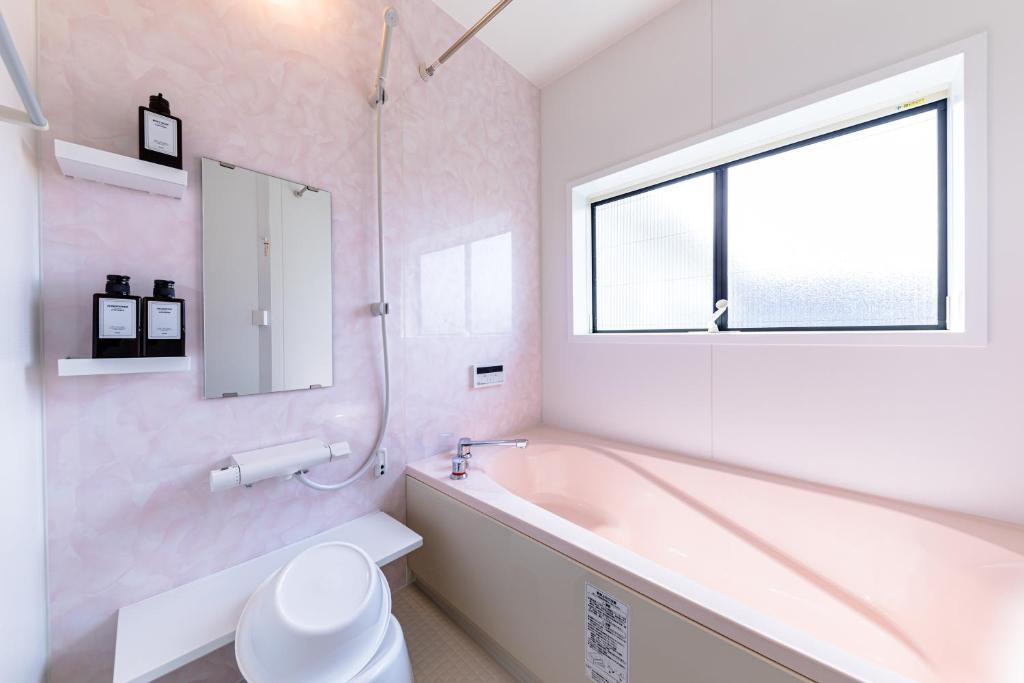 a bathroom with a tub and a toilet and a window at Bon Moment B棟-桜館 in Fujikawaguchiko