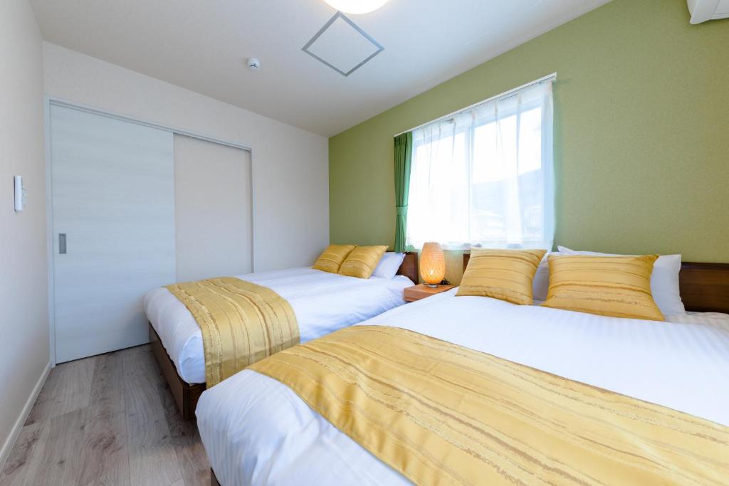 two beds in a room with green walls at Bon Moment B棟-桜館 in Fujikawaguchiko