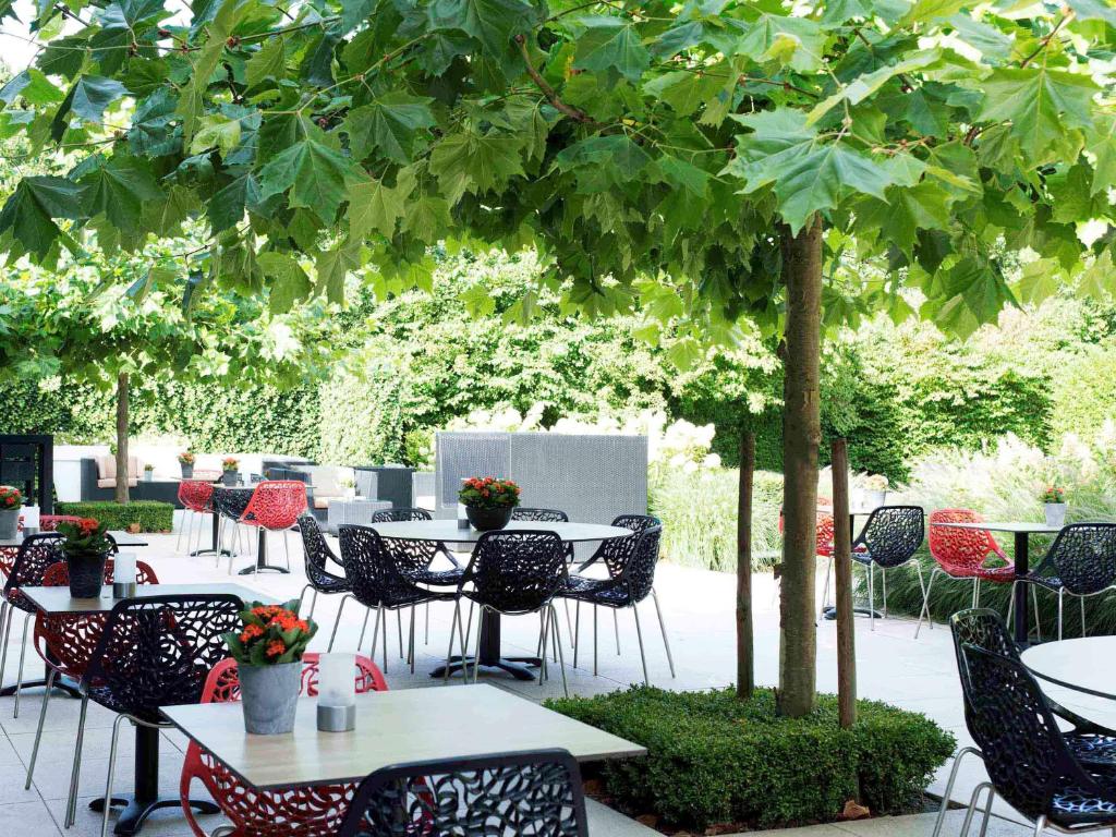 a group of tables and chairs under a tree at Novotel Rotterdam - Schiedam in Schiedam