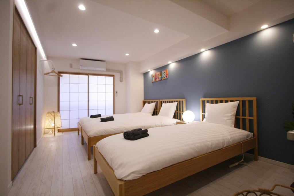 a bedroom with two beds and a blue wall at STAY ARI Kabukicho in Tokyo