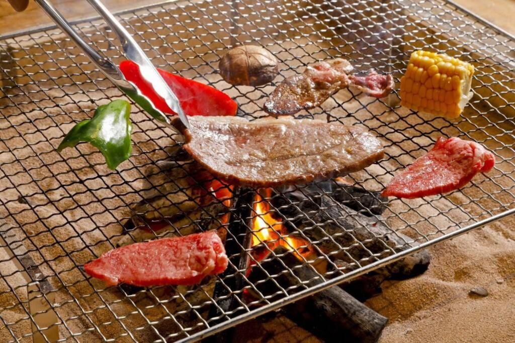 a metal grill with meat and vegetables on it at 炉之宿 淀川 in Osaka