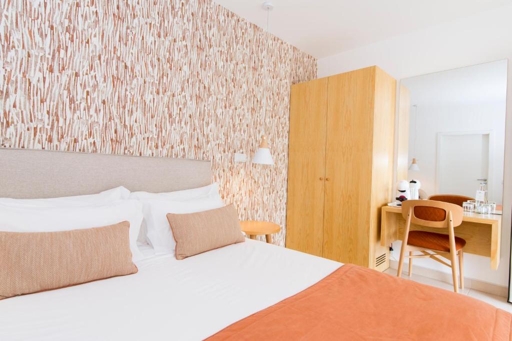 a bedroom with a bed and a desk with a chair at Quinta Dos Perfumes in Tavira