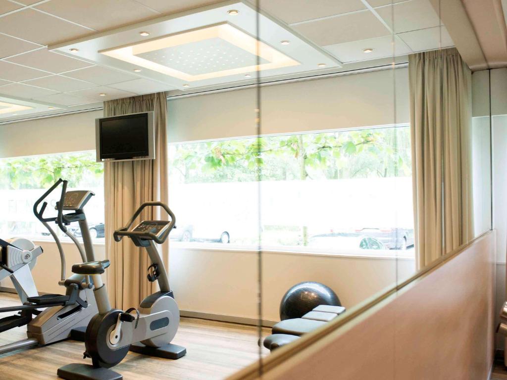 a gym with treadmill ellipticals and a large window at Novotel Rotterdam - Schiedam in Schiedam