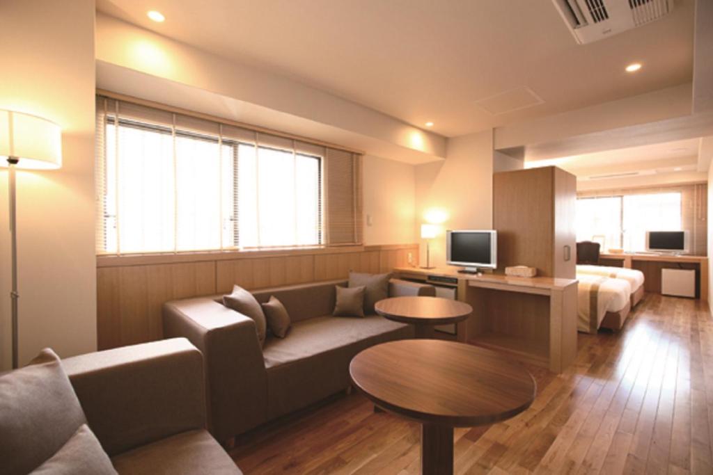 a living room with a couch and a tv at Sutton Place Hotel Ueno in Tokyo