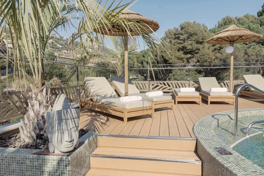 una terraza de madera con sillas y sombrilla en Casa Coco Boutique Hotel & Spa 4*S - Adults Only, en Lloret de Mar