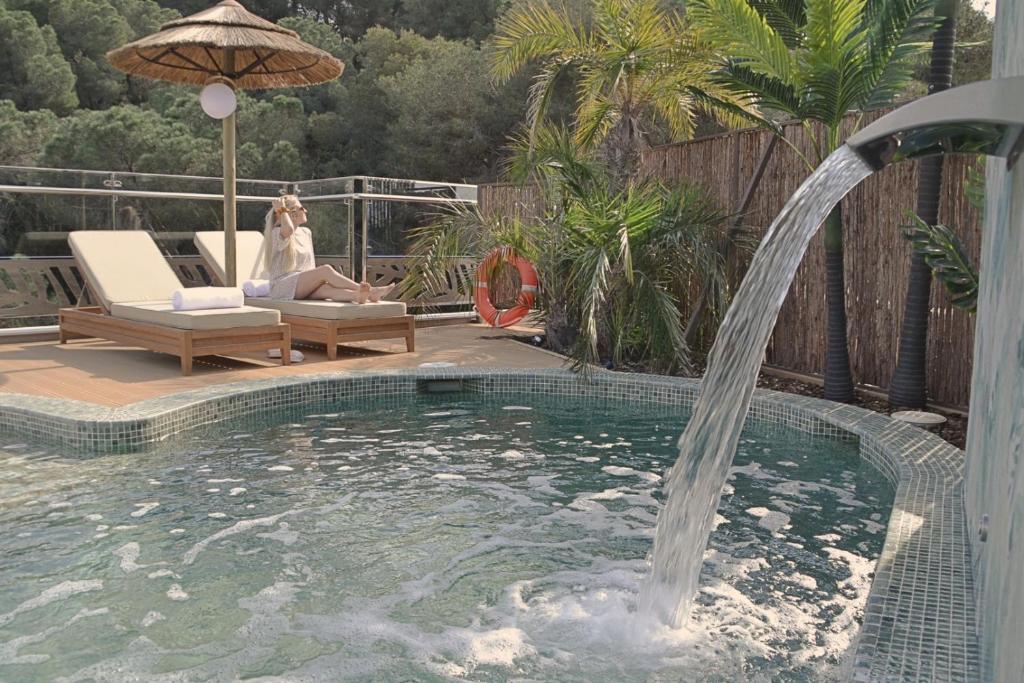 una mujer sentada en una silla junto a una piscina en Casa Coco Boutique Hotel & Spa 4*S - Adults Only, en Lloret de Mar