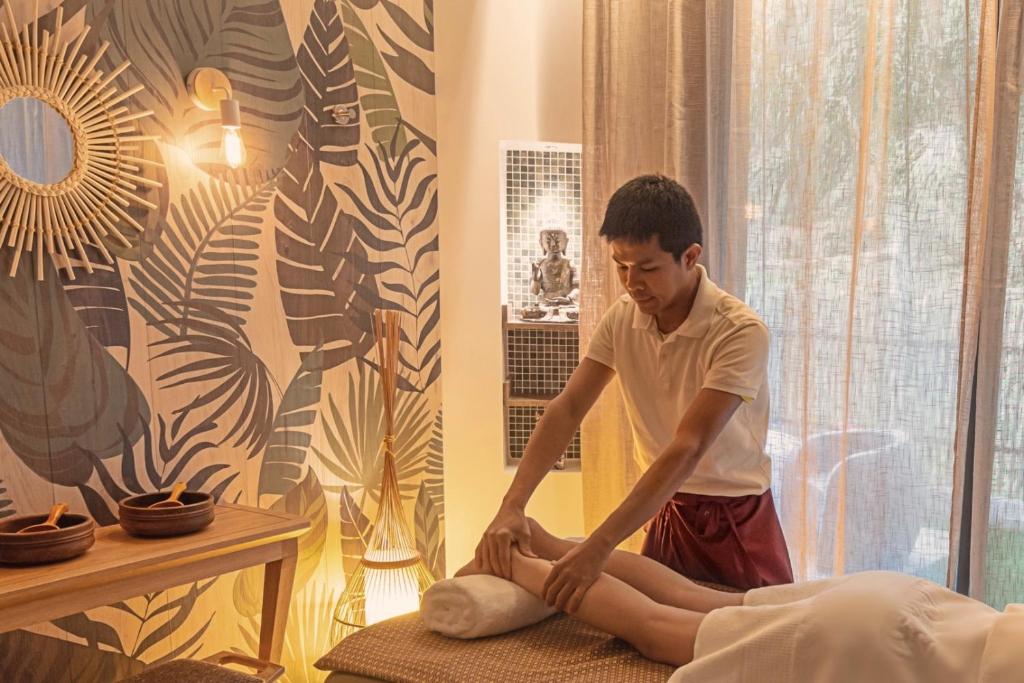 un joven sentado en una cama atado a sus piernas en Casa Coco Boutique Hotel & Spa 4*S - Adults Only, en Lloret de Mar