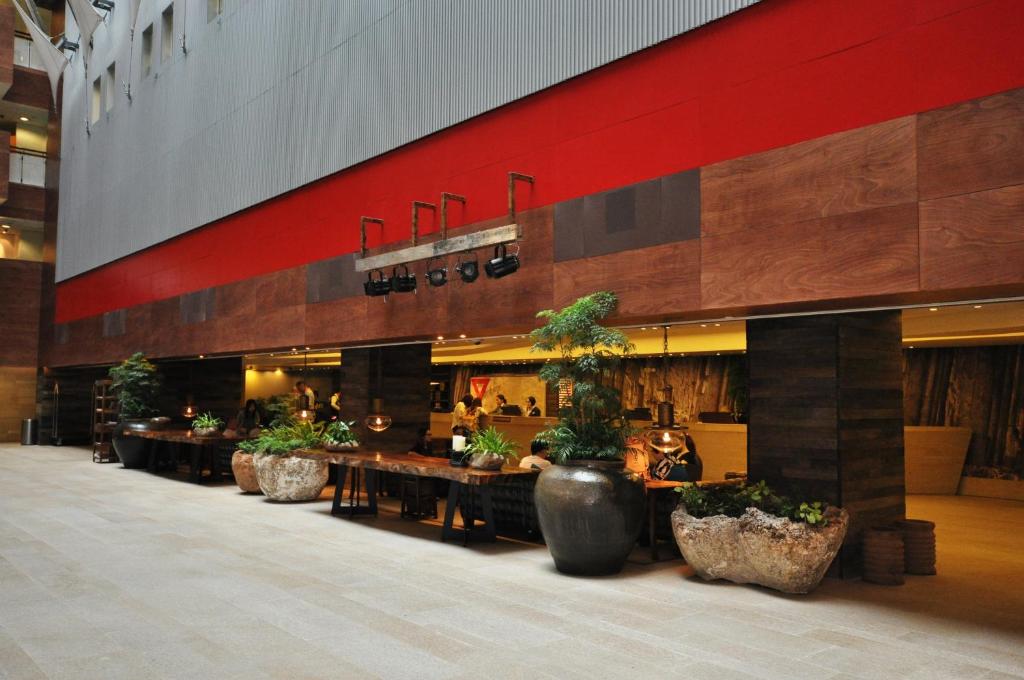 a lobby with tables and potted plants in a building at The Salisbury - YMCA of Hong Kong in Hong Kong