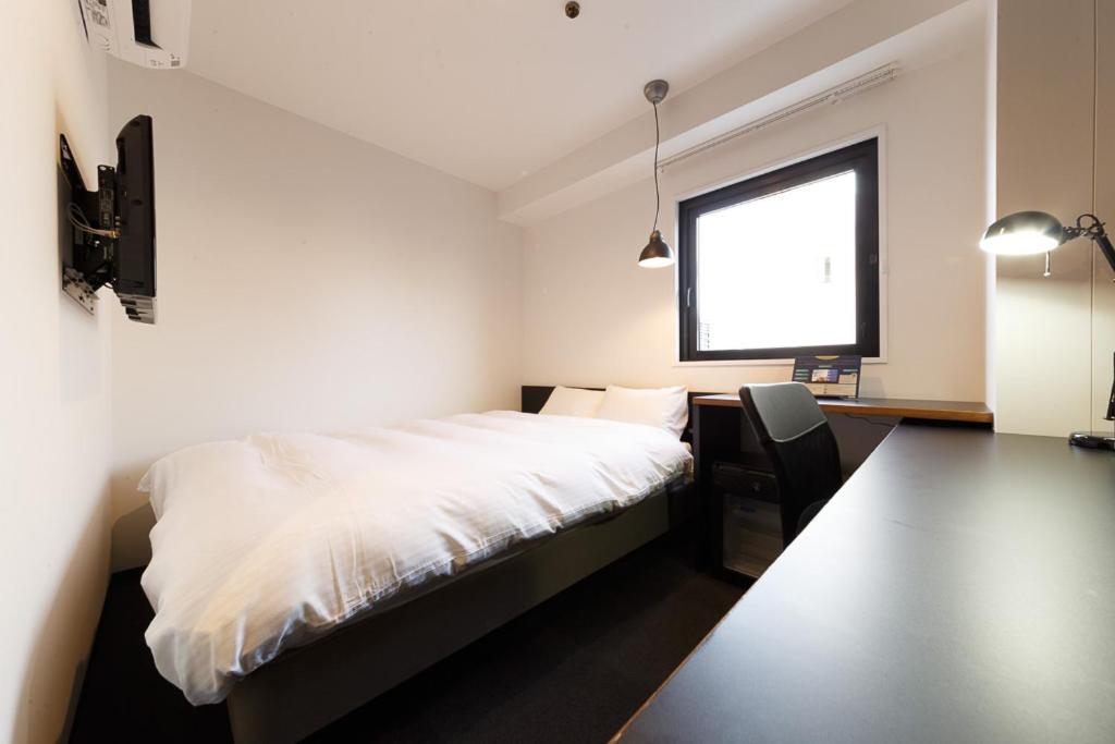 a bedroom with a white bed and a window at Hotel Citio Shizuoka in Shizuoka