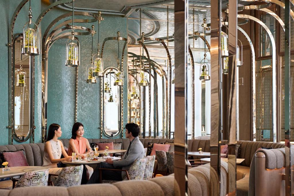 a group of people sitting at tables in a restaurant at Four Seasons Hotel Hong Kong in Hong Kong