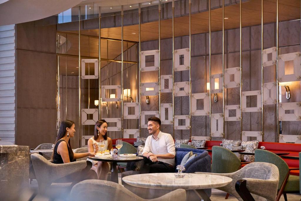 a group of people sitting at tables in a restaurant at Four Seasons Hotel Hong Kong in Hong Kong