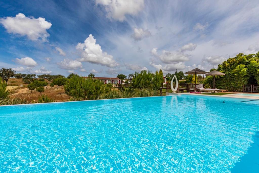 una grande piscina blu con cielo blu di Monte Xisto Country Charm Hotel a Santiago do Cacém