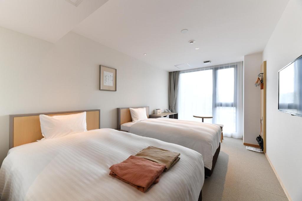 a hotel room with two beds and a television at The Centurion Hotel & Spa Classic Izumo in Izumo