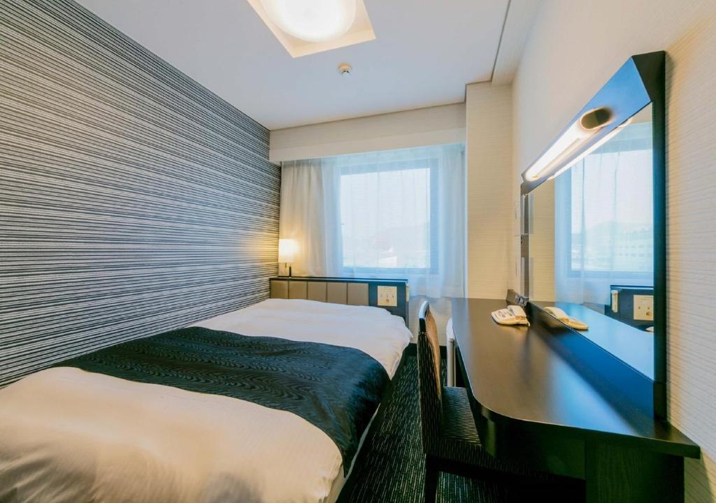 a hotel room with two beds and a window at APA Hotel Nagasaki Ekiminami in Nagasaki