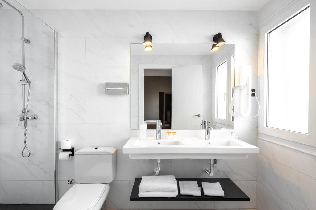 een witte badkamer met een wastafel en een toilet bij Hotel Cortezo in Madrid