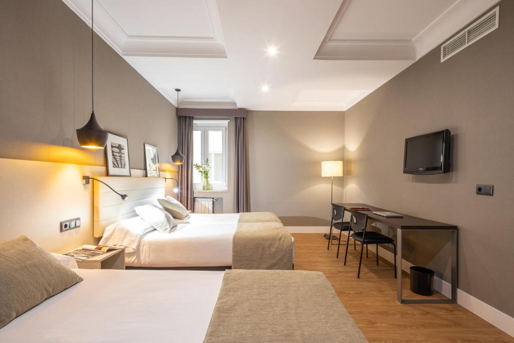 een hotelkamer met twee bedden en een bureau bij Hotel Cortezo in Madrid