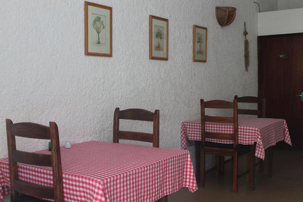 a dining room with two tables and chairs with red and white table cloth at Auberge Miko in Grand Baie