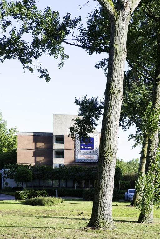 a tree in the grass in front of a building at Novotel Rotterdam - Schiedam in Schiedam