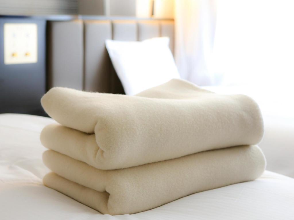 a pile of towels sitting on top of a bed at APA Hotel Nagasaki Dejima in Nagasaki