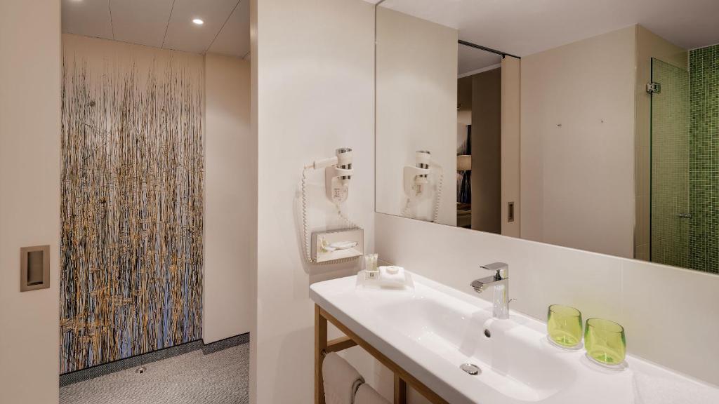 um banheiro branco com uma pia e um espelho em Holiday Inn Frankfurt - Alte Oper by IHG em Frankfurt am Main