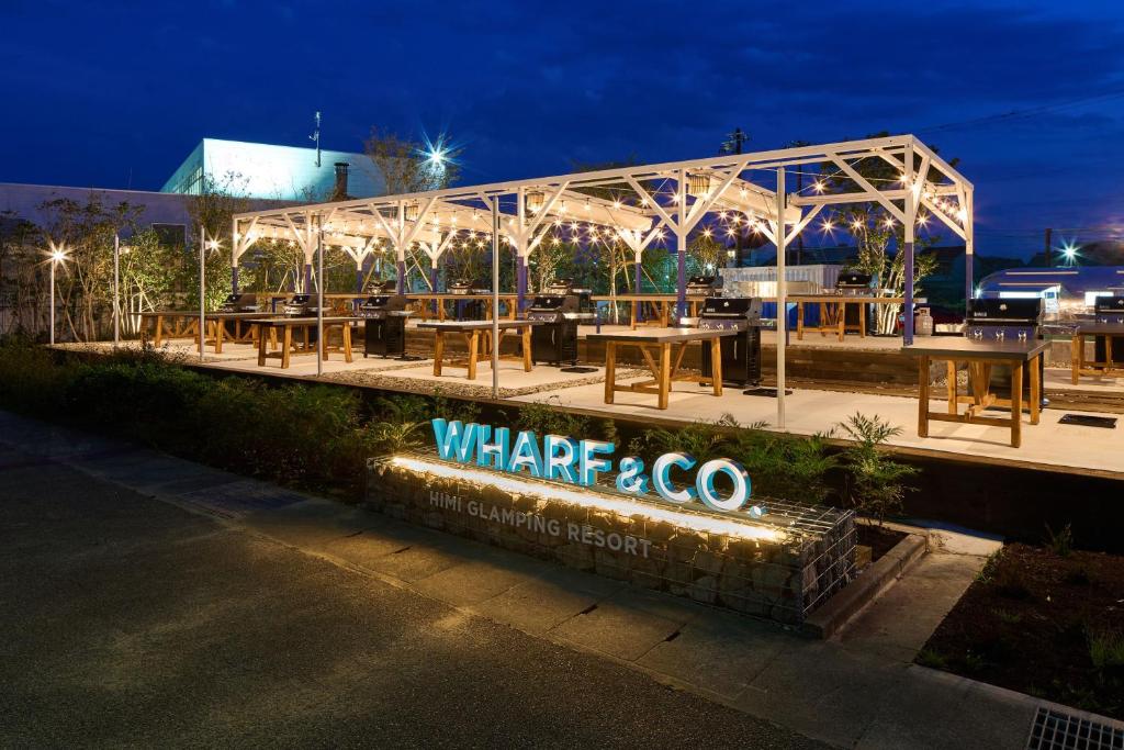 a restaurant with wooden tables and a lit up sign at WHARFandCO in Himi