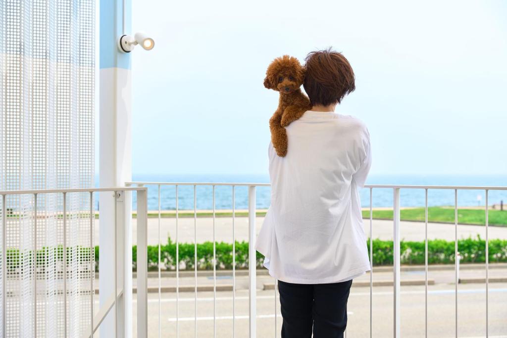a woman holding a teddy bear looking out of a window at WHARFandCO in Himi