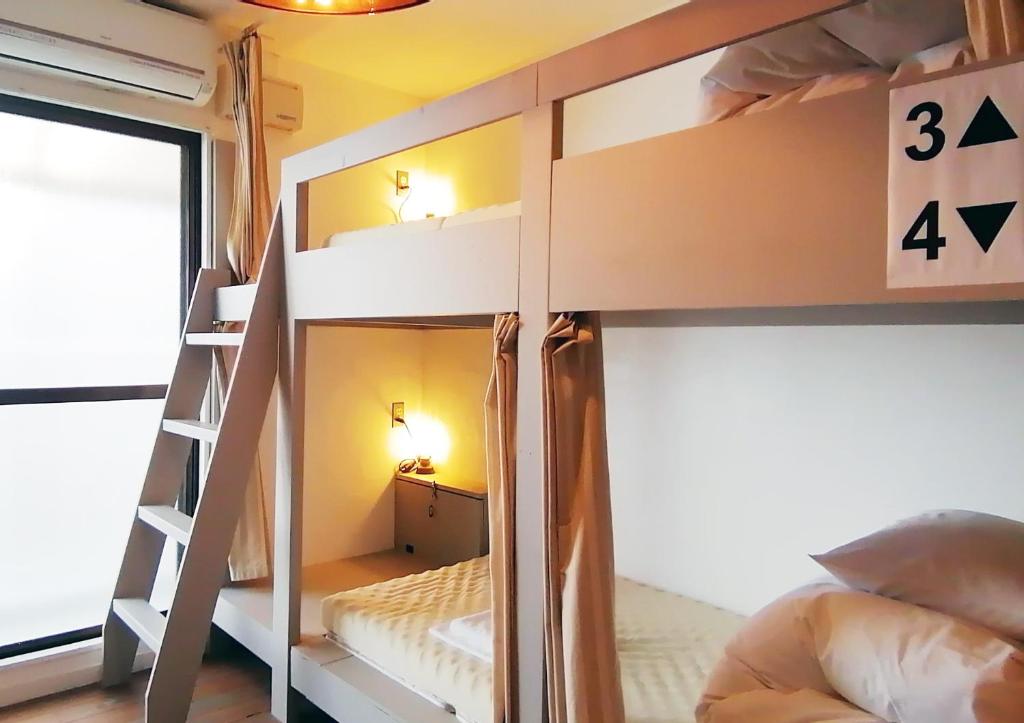 a bunk bed room with two bunk beds and a ladder at Ten to Sen Guesthouse in Takamatsu