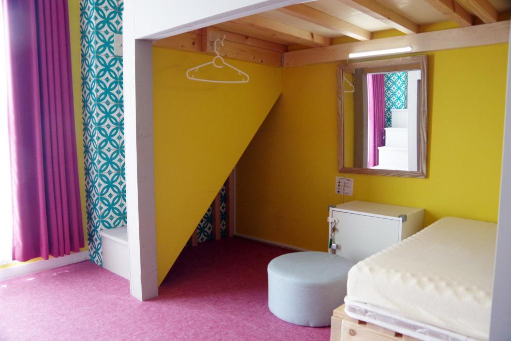 a yellow room with a bed and a window at Ten to Sen Guesthouse in Takamatsu
