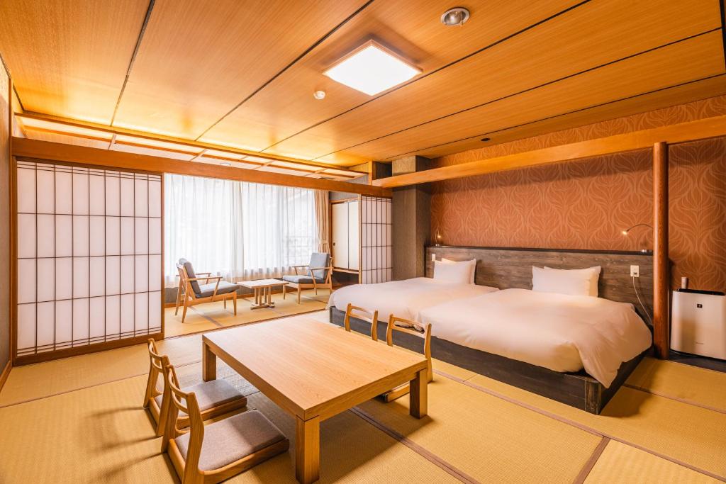a bedroom with a bed and a table in it at Atarayo Nishiizu Onsen in Izu