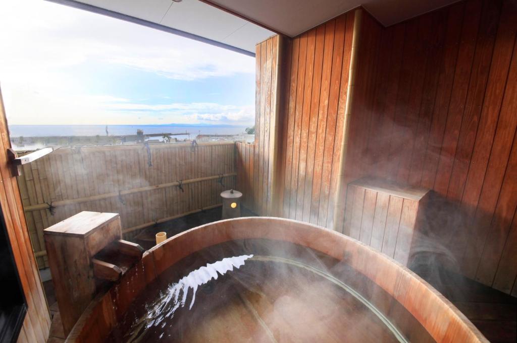 a large wooden bath tub with a large window at Atarayo Nishiizu Onsen in Izu