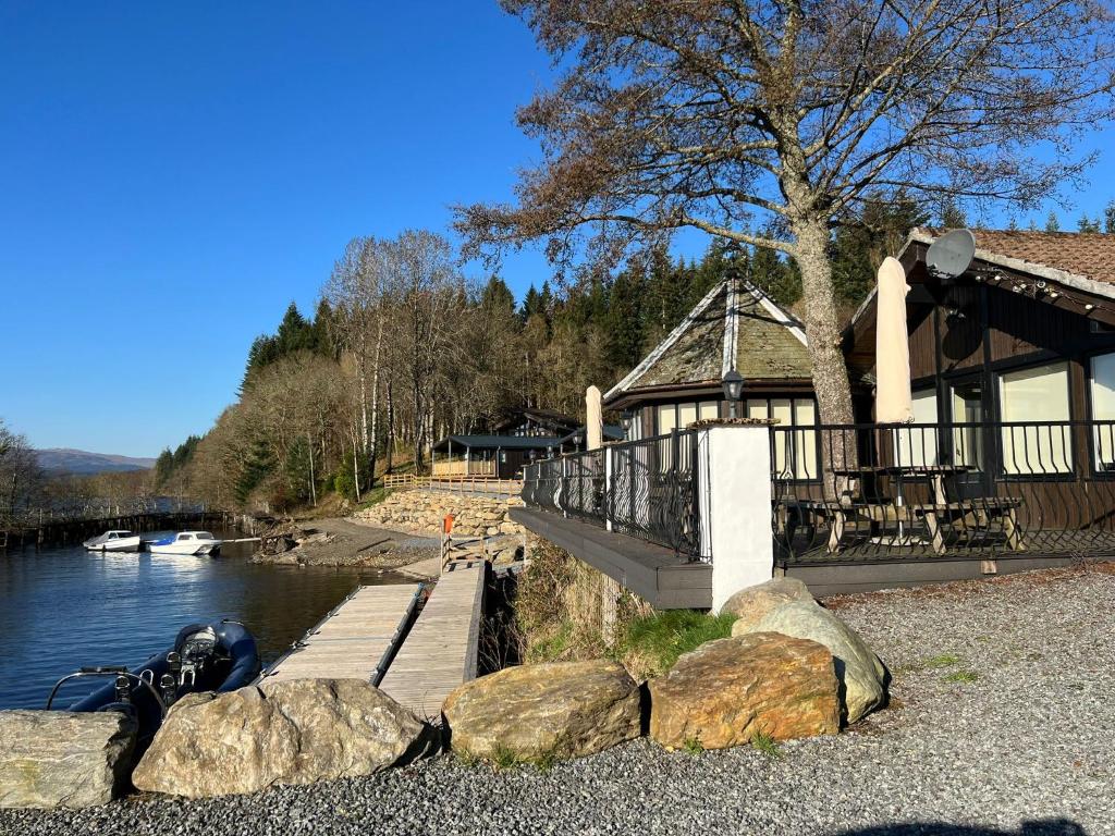 a building with a dock next to a river at LOCH TAY HIGHLAND LODGES and GLAMPING PARK in Morenish