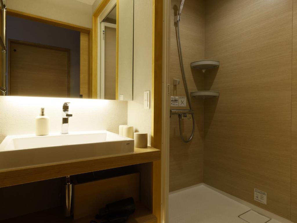 a bathroom with a sink and a shower with a mirror at Ohashikan in Matsue