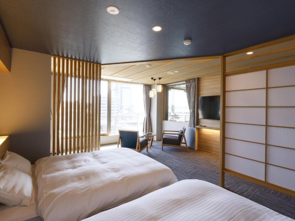 a hotel room with two beds and a television at Ohashikan in Matsue